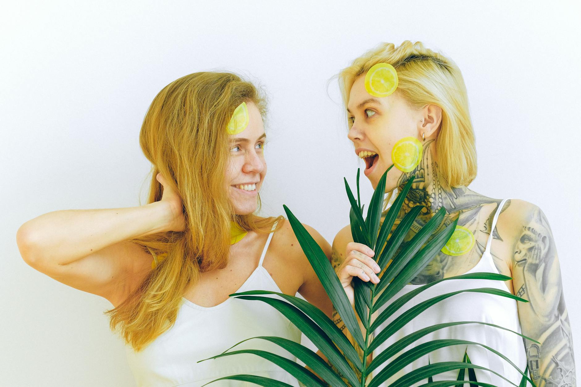 Two women smiling with fresh lemons, expressing joy and comfort indoors
