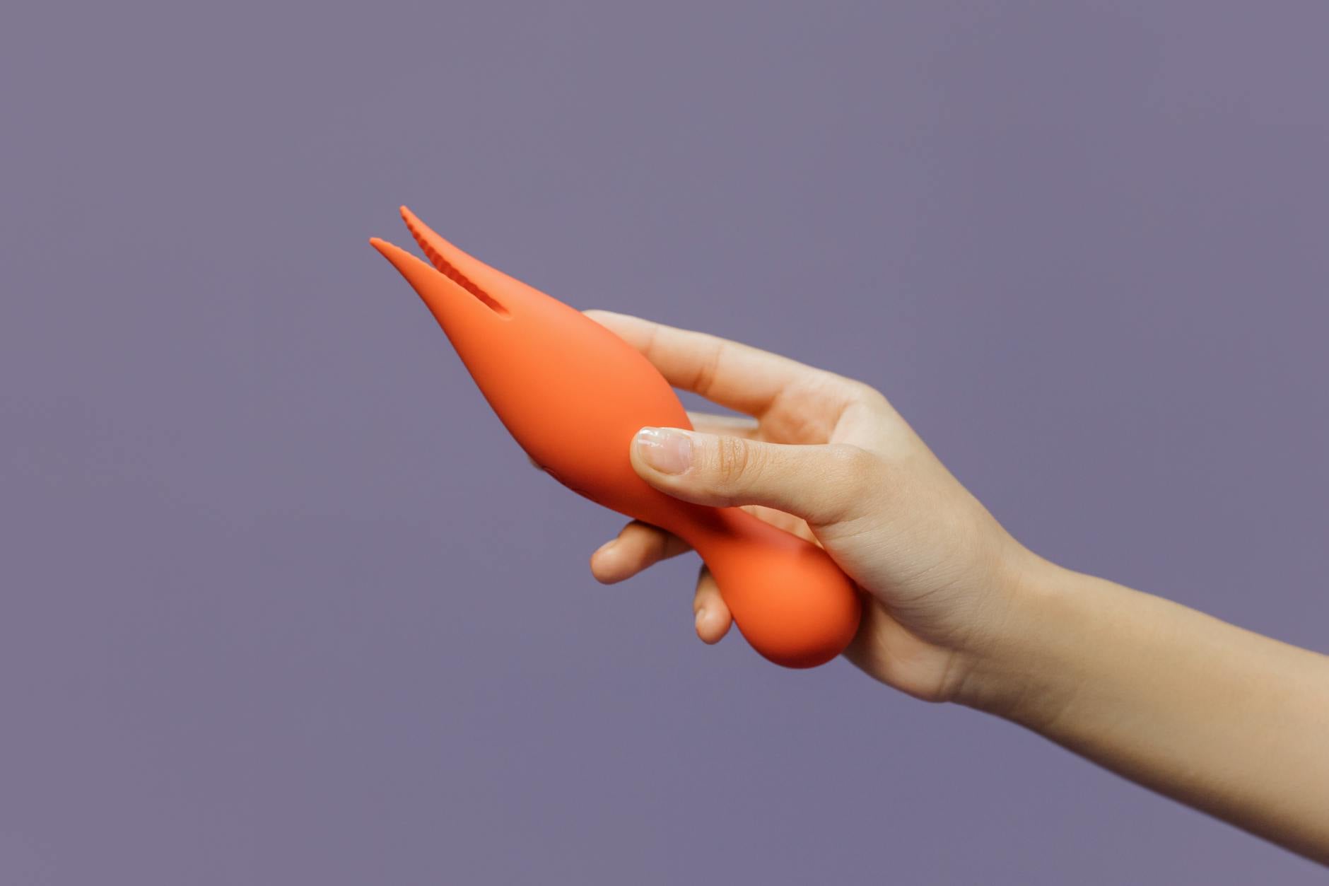 Hand holding a lemon vibrator against a minimalist purple backdrop, showcasing modern pleasure technology