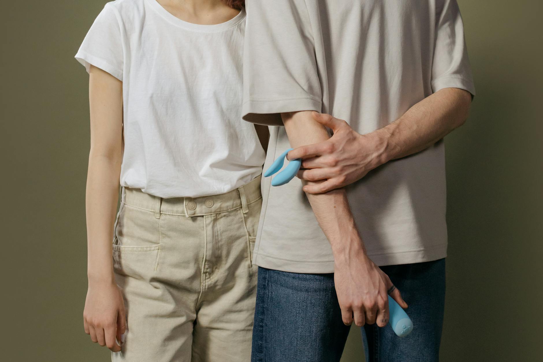 Hands holding a sleek blue vibrator against a purple background, symbolizing intimate self-exploration