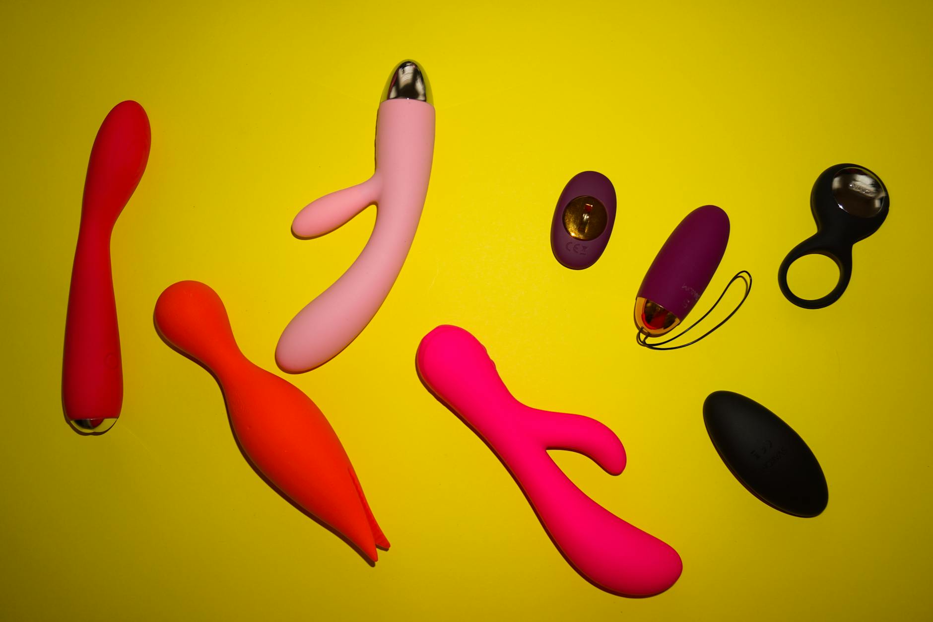 Hand reaching toward colorful silicone toys on a table, symbolizing shared pleasure and connection