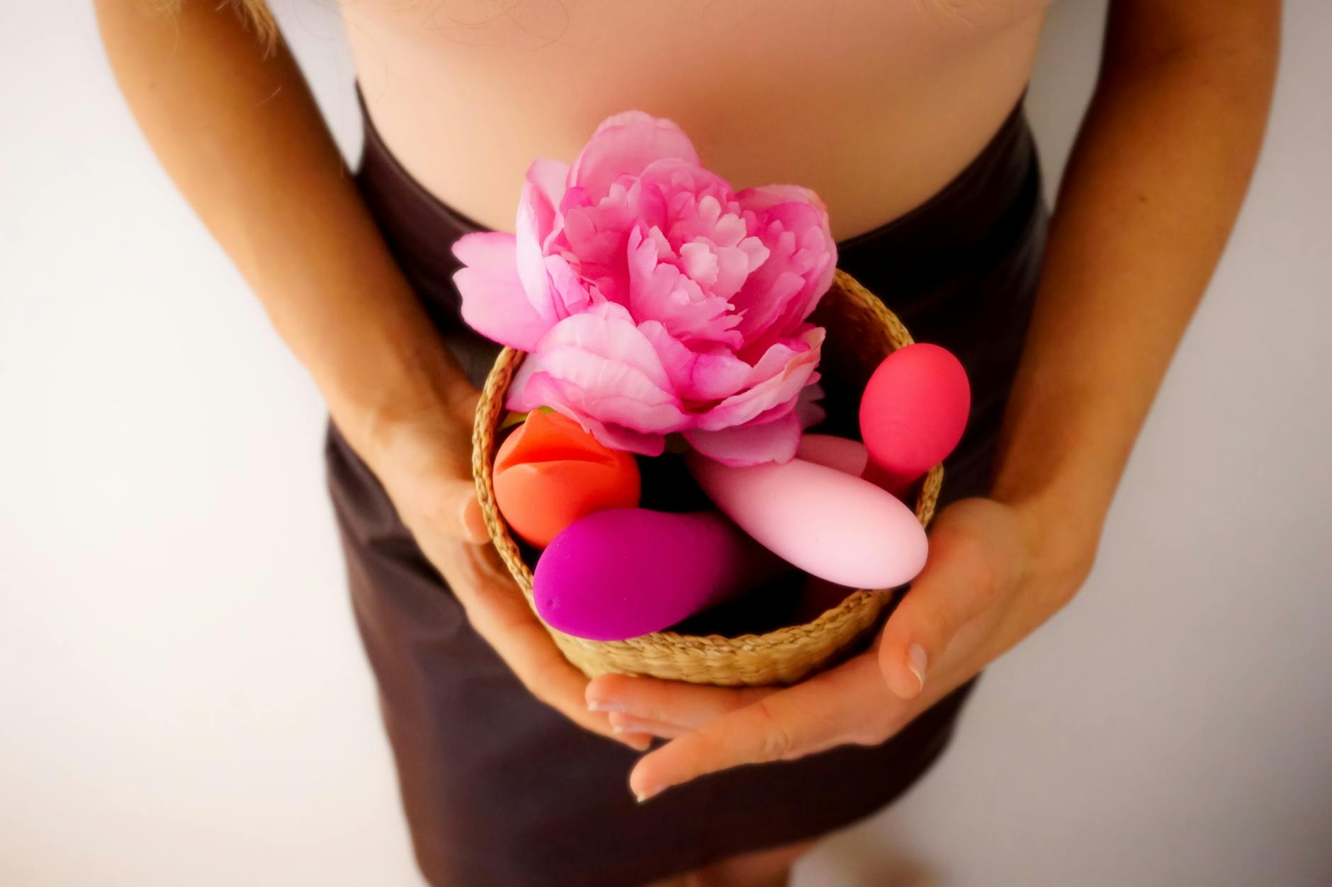 Woman holding blue and pink clitoral vibrators during emotional recovery