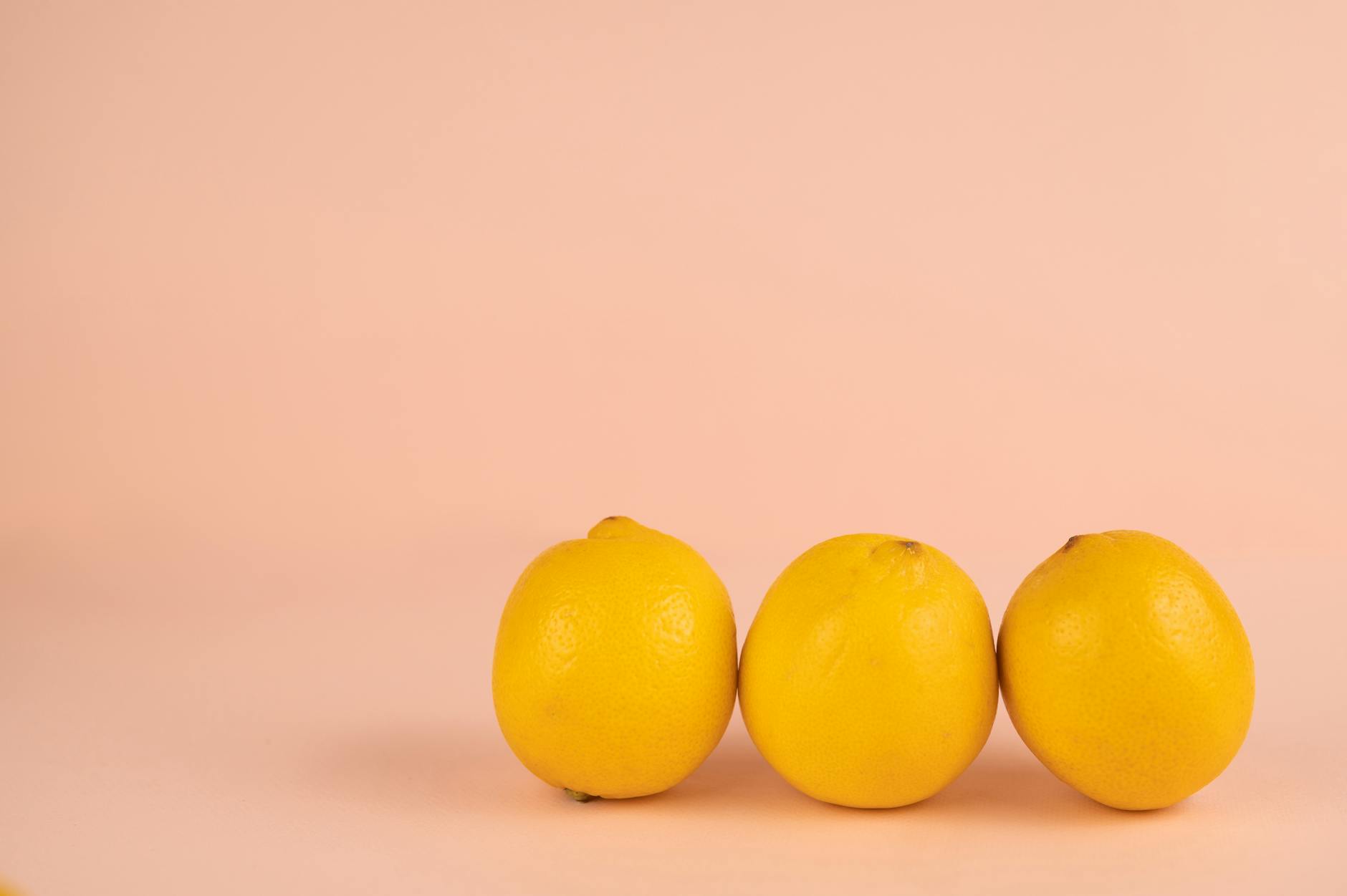 Bright yellow lemons arranged on a soft pastel background, symbolizing freshness and intentional pleasure