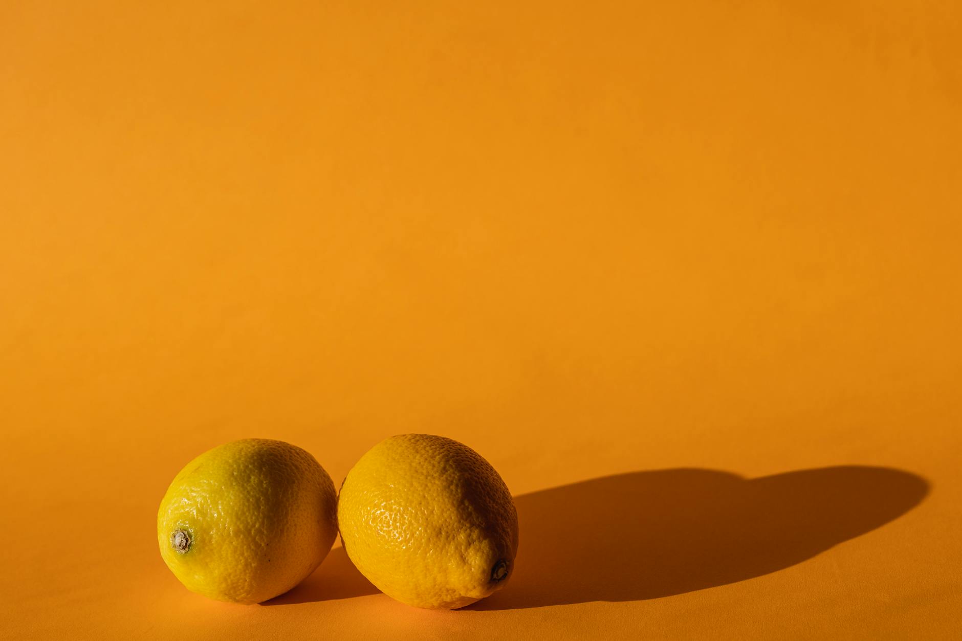 Bright fresh lemons arranged on a yellow background, symbolizing the bright sensation of clitoral stimulation